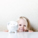 Young, happy girl standing with her piggy bank